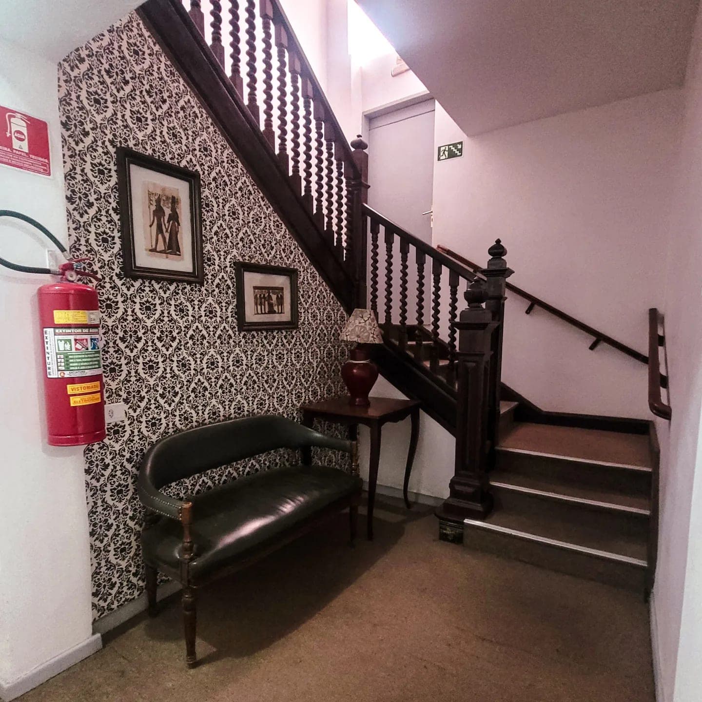 Área social do Hotel Dona Lú, com banco antigo junto à escadaria